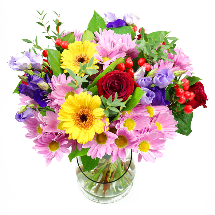 A vibrant mixed-colour bouquet is showcased here, its blooms gathered in a clear glass vase and set against a crisp white backdrop, allowing each detail to be seen as if you were standing at the counter of a Biggin Hill florist. At the heart of the design, deep red roses unfurl in velvety spirals, their rich hue conveying a sense of affection and sincere feeling. Next to them, two bright yellow gerbera daisies with warm, dark centres form cheerful focal points, their large, flat faces radiating energy much like sunshine spilling over the surrounding hills. Encircling these key blooms is a generous layer of soft pink daisies or chrysanthemums, their many slender petals and golden centres forming a soft, rounded cushion that gives the bouquet fullness and approachability. Punctuating the pastel pinks are graceful lisianthus flowers in purple and pale lavender, their gently flared, bell-shaped petals adding cooler notes and a slightly romantic, country-garden charm. Scattered through the arrangement are glossy red hypericum berries, their small, spherical shapes offering a tactile contrast to the surrounding petals. Various types of green foliage frame the entire composition, with broad, dark leaves and lighter, more delicate stems combining to create both structure and natural movement. Through the transparent glass vase, neatly trimmed stems can be seen standing in clear water, evidence of the careful preparation that keeps the flowers fresh from delivery to display. The overall impression is of a joyful, thoughtfully balanced bouquet, perfect as a centrepiece for a family meal after a walk near Biggin Hill Airport, or as a bright and heartfelt floral gift for birthdays, congratulations, or to bring colour and comfort into someone's home.